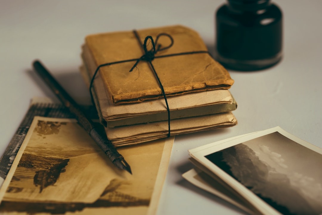 Een brievenset met inktpen en inktdoosje. Er naast liggen oude fotos