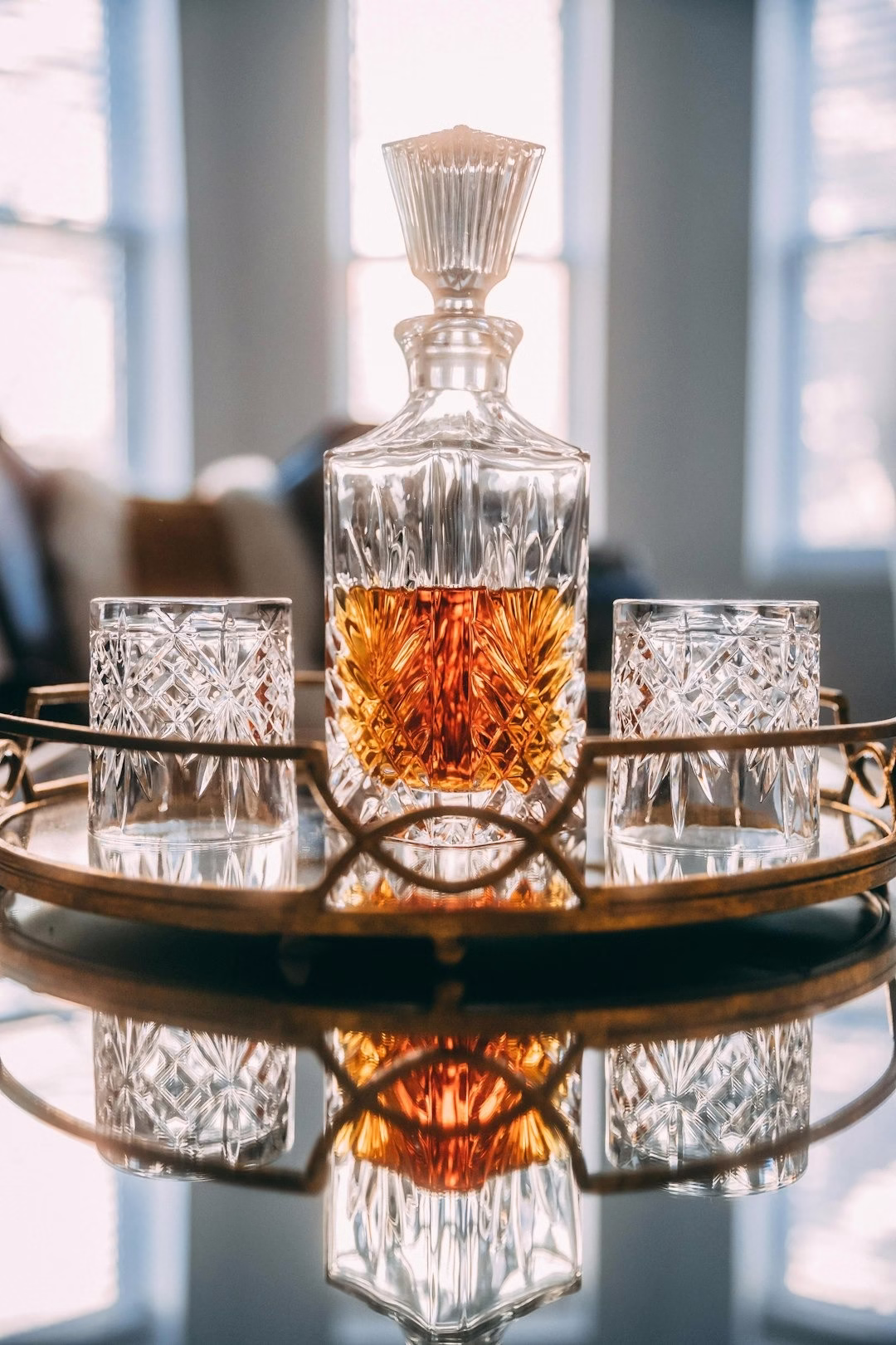 whiskeyfles, half gevuld, met 2 whiskeyglazen over de kop ernaast